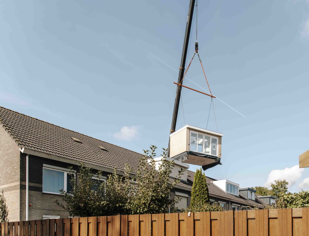 prefab aanbouw hangt in hijskraan