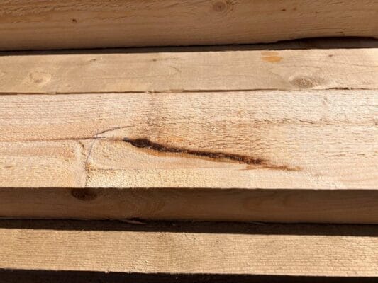 Een topscheur in het hout. Deze mag in US niet groter zijn dan 10% van de breedte, in V is dit 30% en in klasse VI mag het 50% zijn.